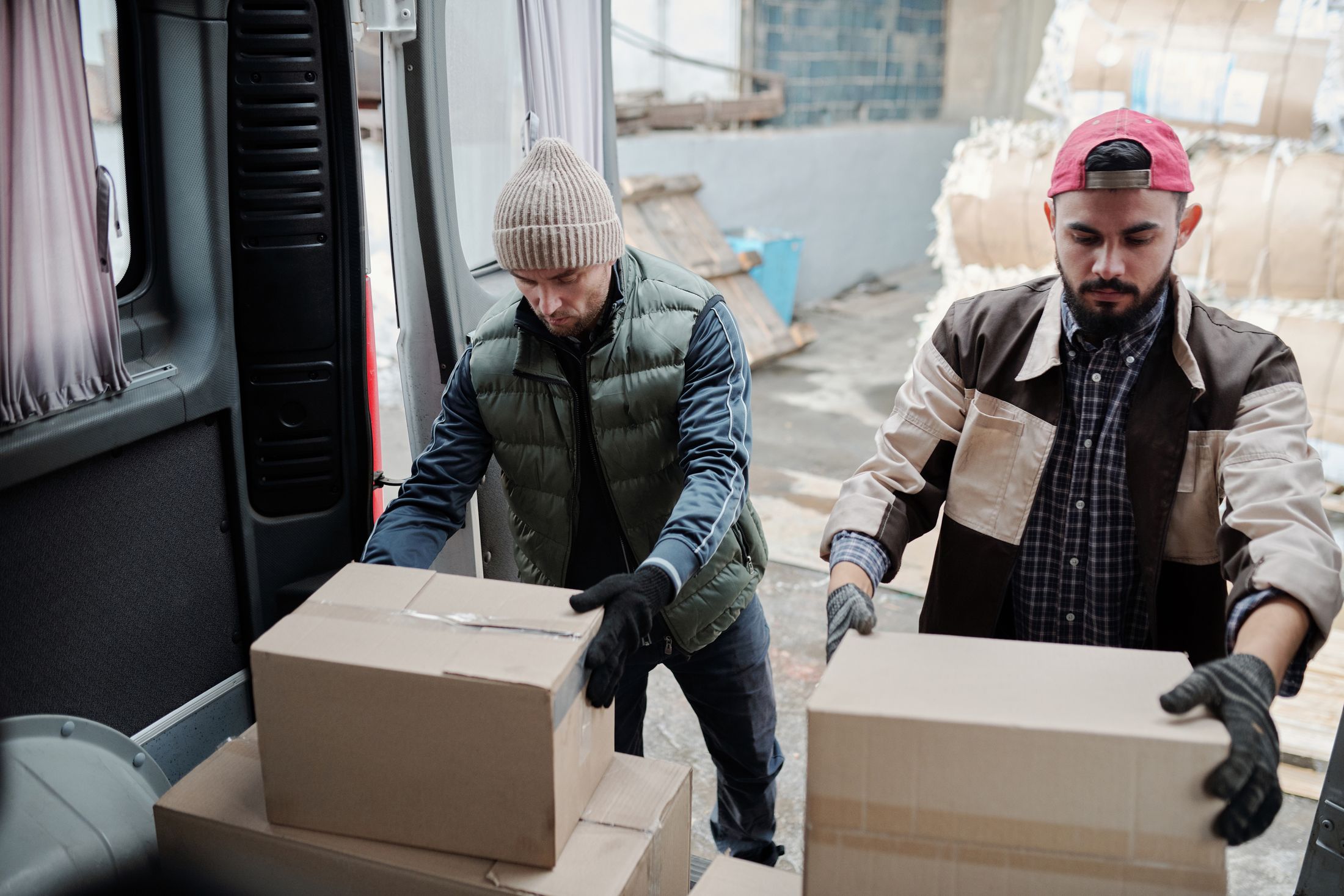 Two logistics workers loading packages into a cargo van